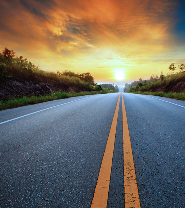 Open two-lane road at sunrise, symbolizing connectivity and opportunity for safe and secure fleet journeys.