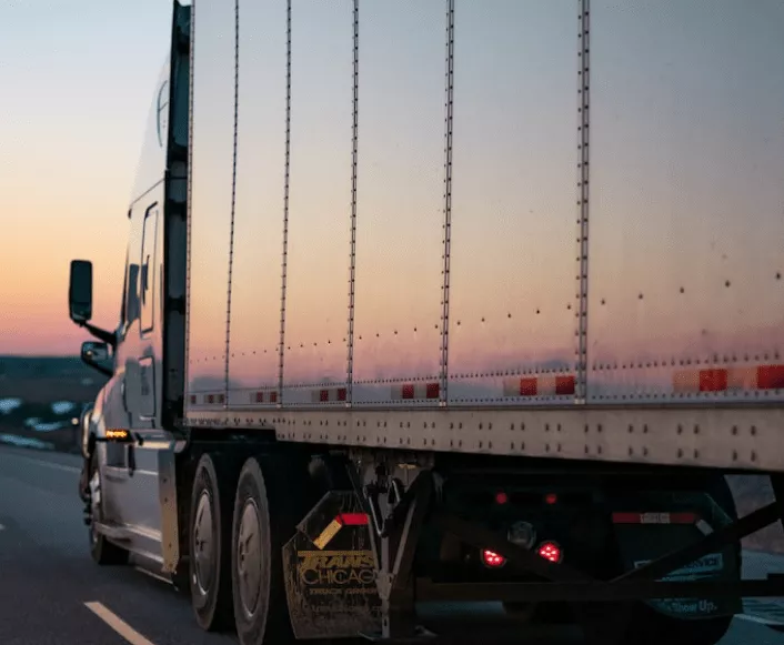 Side view of a dry van on a highway at sunrise