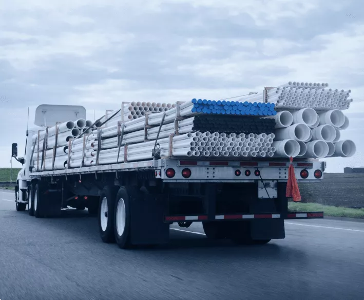 Flatbed trailer hauling PVC pipes on a highway