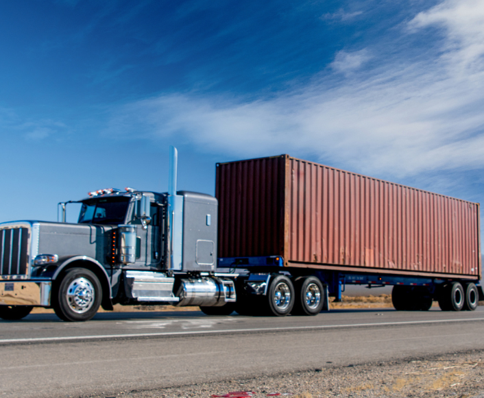 Chassis trailer with a shipping container on a highway under a clear sky