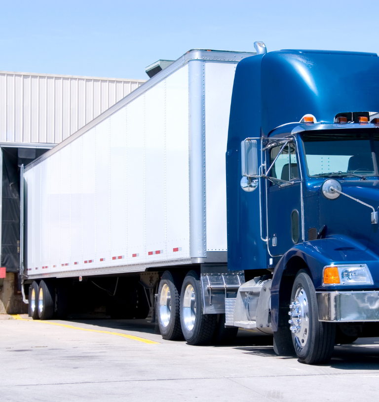 Blue semi with dry van docked at a loading bay, representing trailer detention