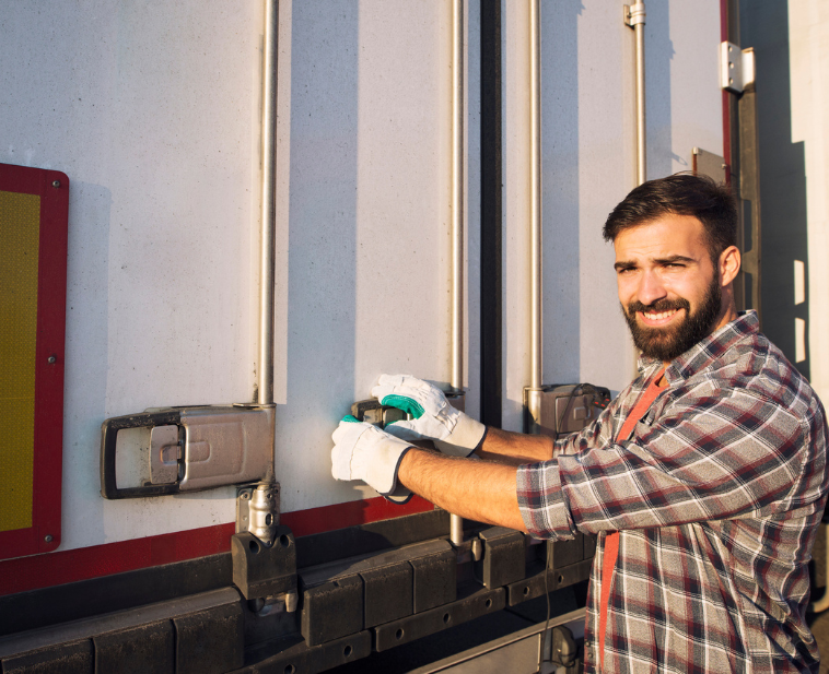 Driving securing the back doors of a trailer, symbolizing door access and the importance of monitoring trailer doors and cargo