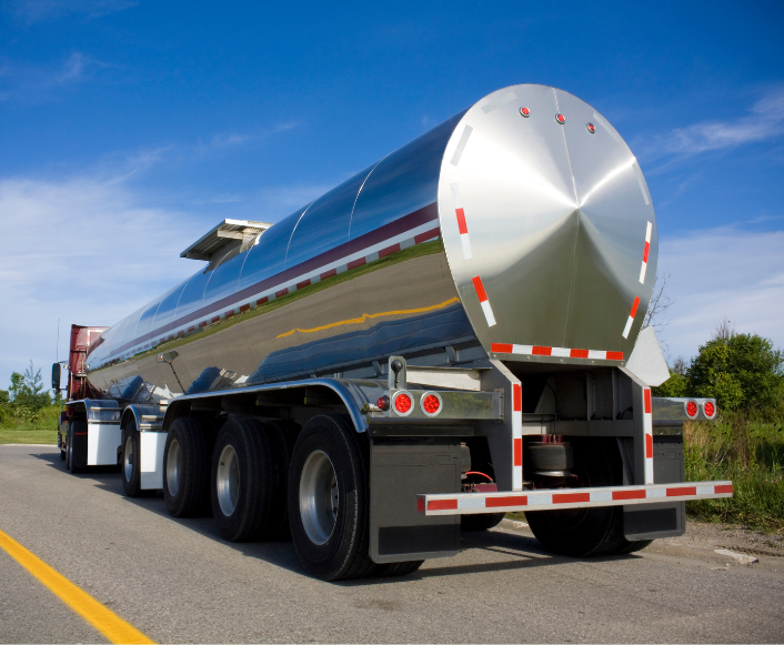 Tanker trailer parked on the side of the road under a blue sky