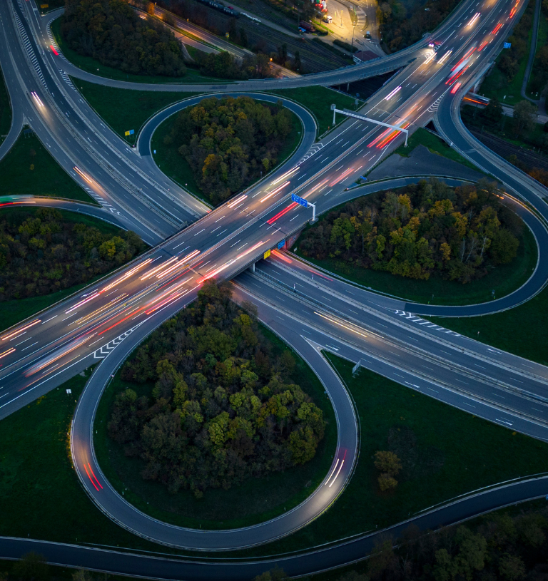 Aerial view of a busy highway interchange at night with light trails symbolizing movement and connectivity