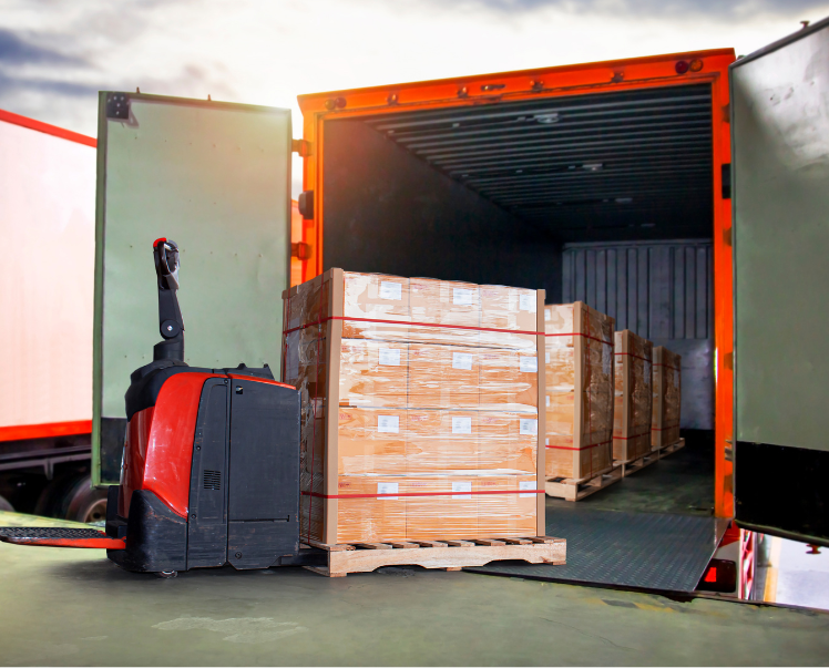 Forklift loading palletized cargo into a semi-trailer at a distribution dock